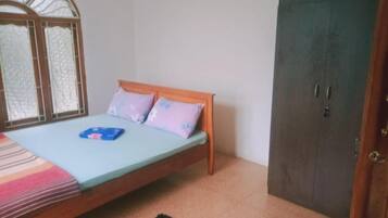 A bedroom with a bed, a wardrobe, and a window with a decorative grille.