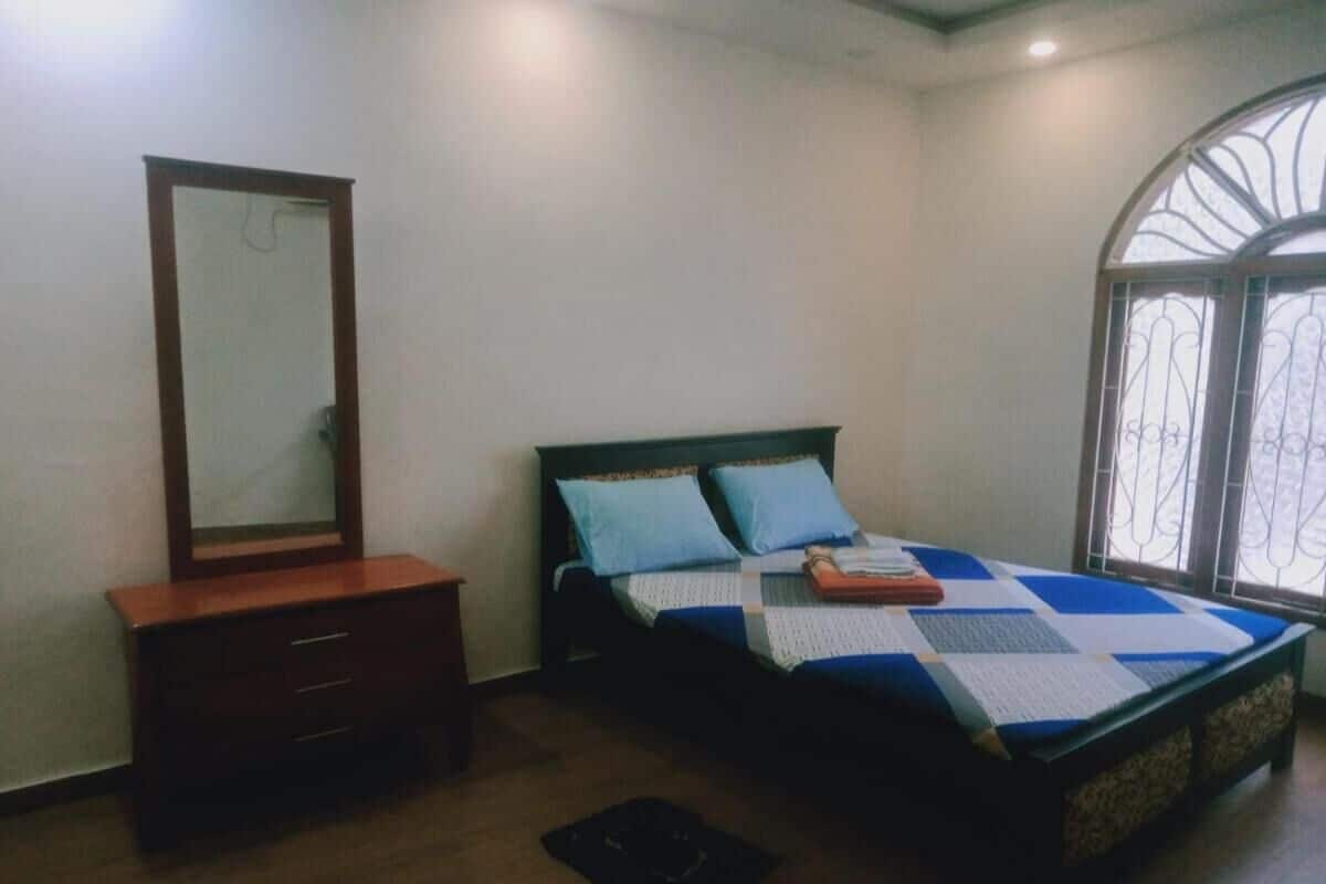 A bedroom with a bed, a dresser, a mirror, and a window.