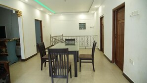 A dining area with a table and chairs, a balcony with a railing, and a view of the outside. - Sobia Villa (Jaffna)