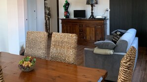 A dining area with a wooden table and wicker chairs, a sofa, and a television on a wooden cabinet. - Cozy apartment 2 steps from Rome finely renovated and equipped (Marino)