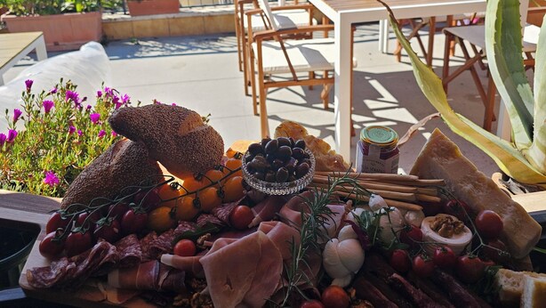 A rooftop terrace with a wooden table set with various cheeses, meats, and olives. - Elegance and relaxation between Rome and Florence, in the heart of central Italy (Giove)