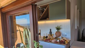 A kitchen with a wooden door, a potted plant, and a variety of food items on the counter. - Elegance and relaxation between Rome and Florence, in the heart of central Italy (Giove)