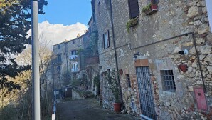 A narrow street with stone buildings, a street lamp, and a clear blue sky. - Elegance and relaxation between Rome and Florence, in the heart of central Italy (Giove)