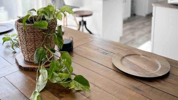 Une cuisine moderne avec des armoires blanches, une table à manger en bois et un luminaire suspendu.