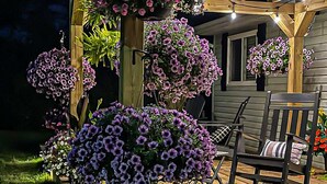 Une terrasse en bois agrémentée de jardinières suspendues et d’une chaise.