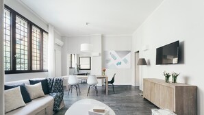 A modern living room with a sofa, coffee table, and dining area. - Tristano e Isotta: Bright Three-room 6 Adults (Bologna)