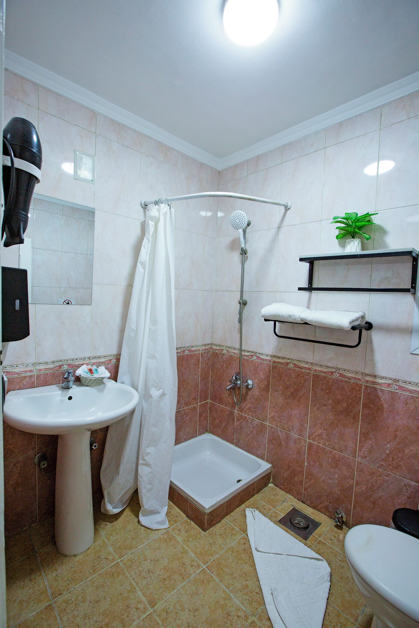 A bathroom with a sink, shower, toilet, and a towel rack.