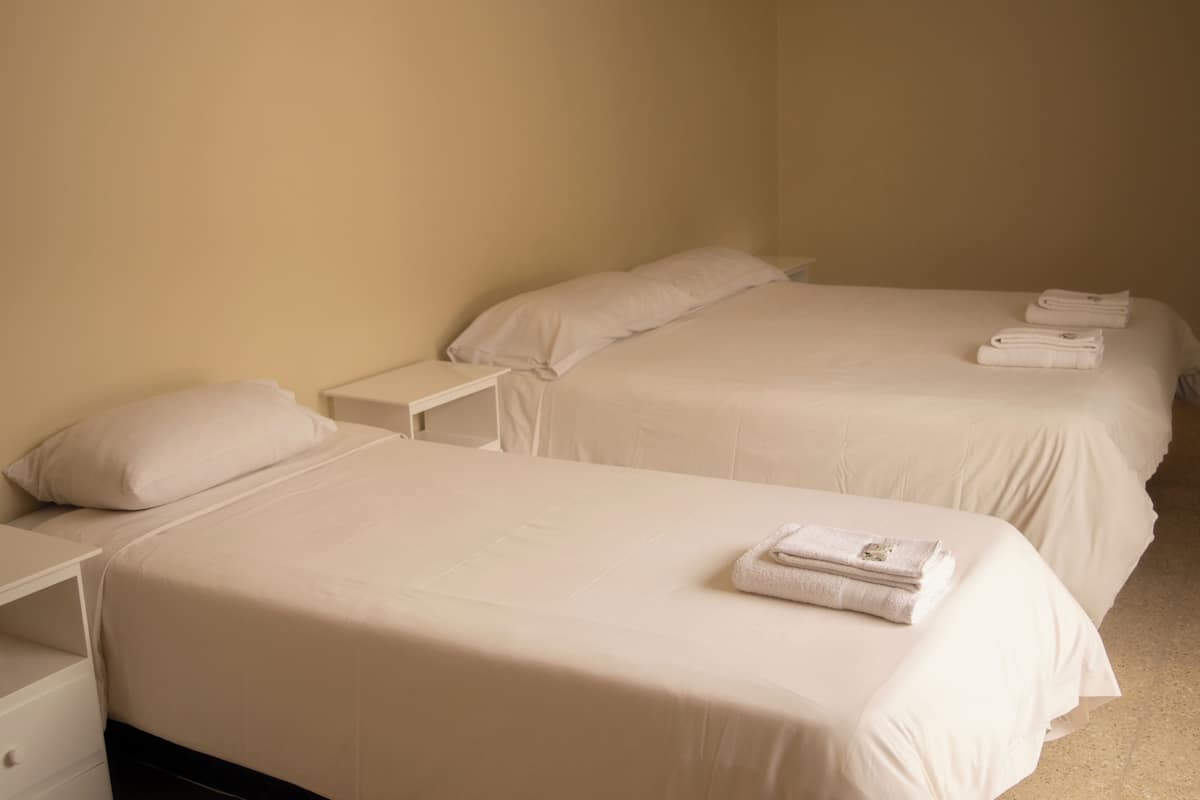 A hotel room with two beds, each with a pillow and a folded towel.