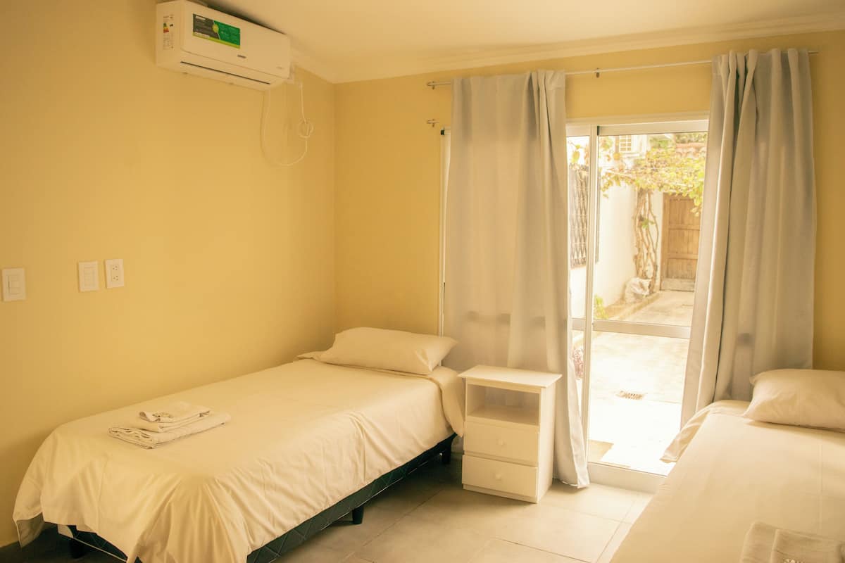 A small, single-bed room with a sliding glass door leading to a balcony.