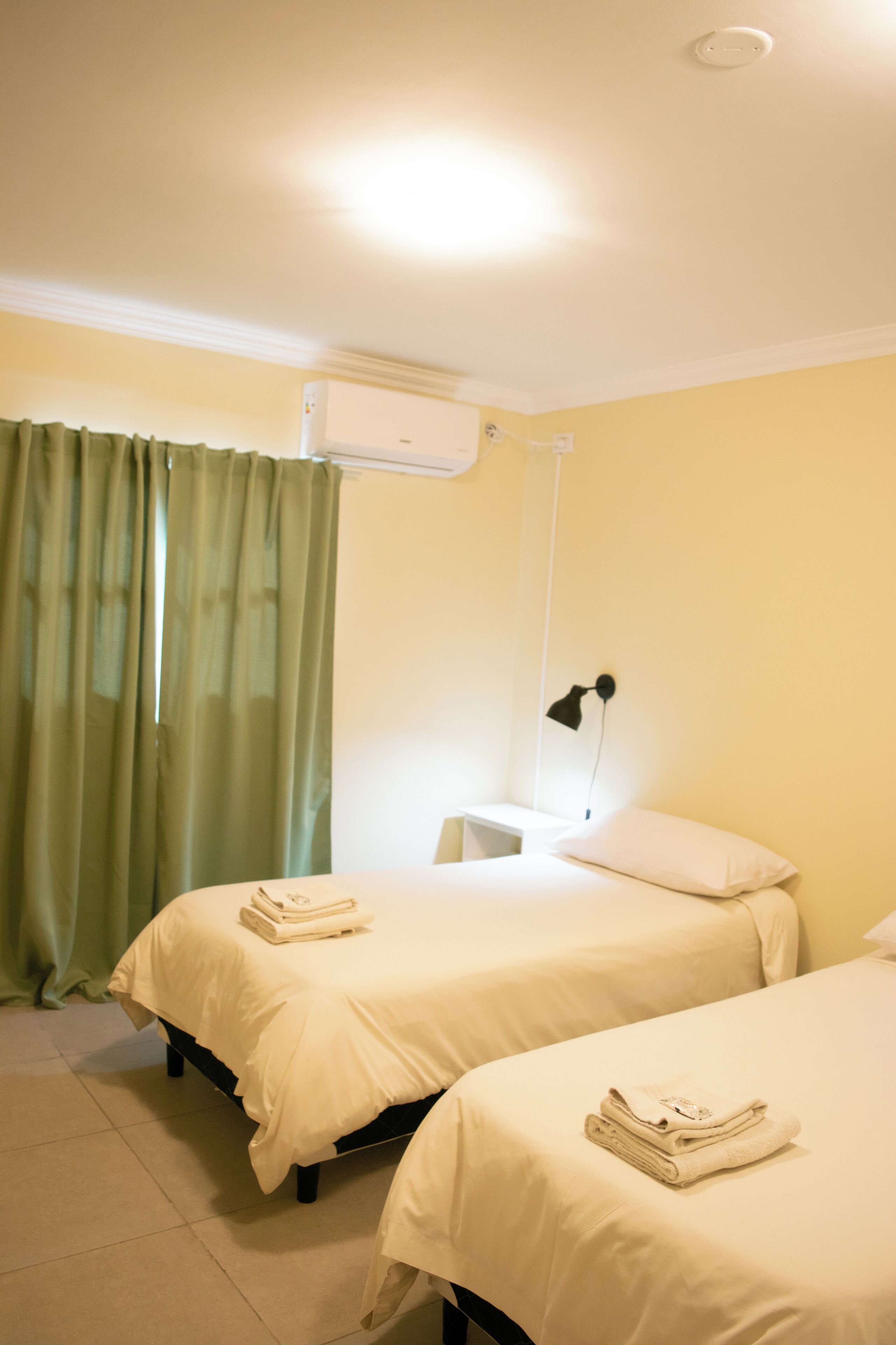 Une chambre d’hôtel avec deux lits, un bureau et un appareil de climatisation.