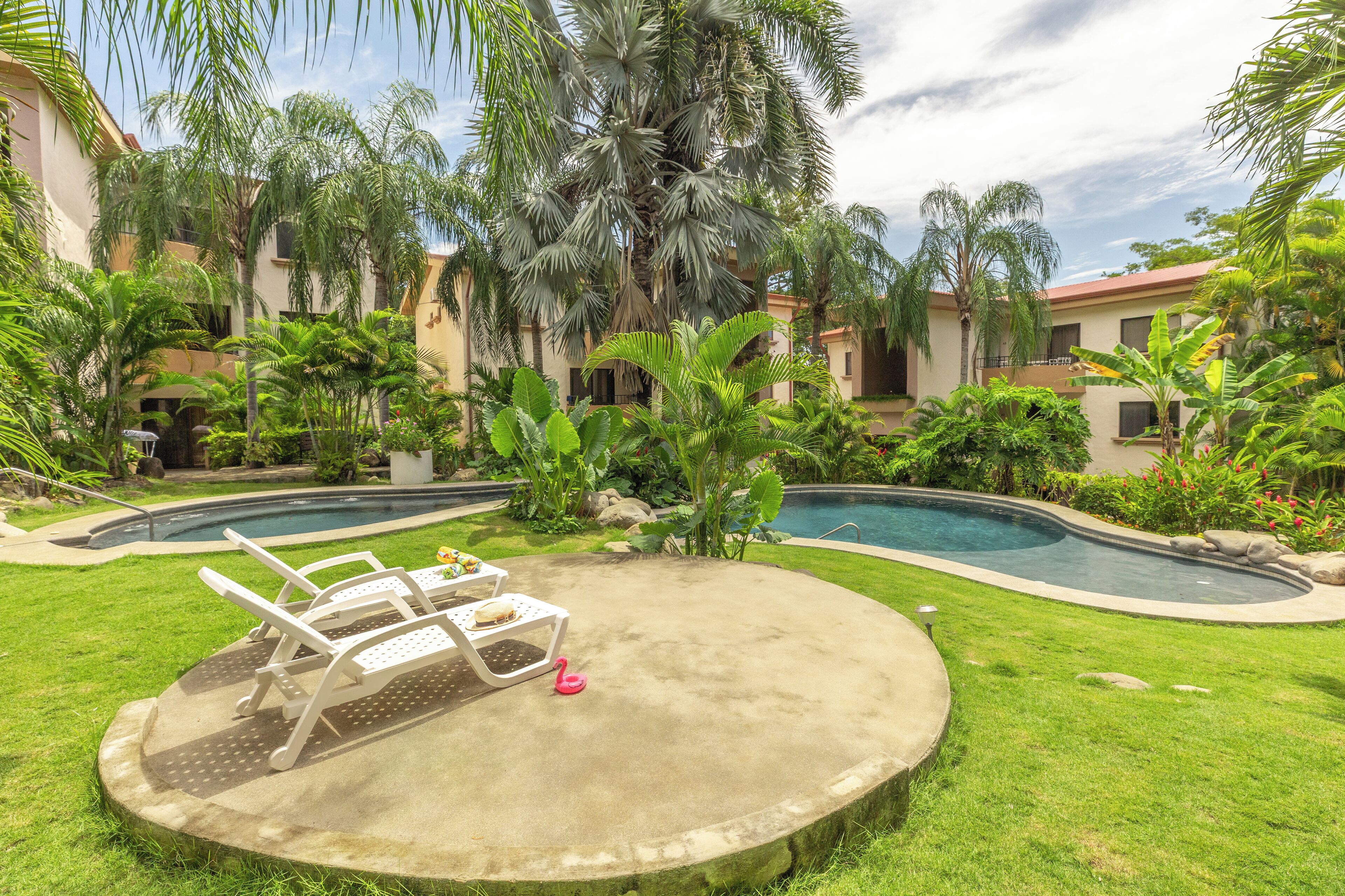 A pool area with lounge chairs and a small pink flamingo statue.