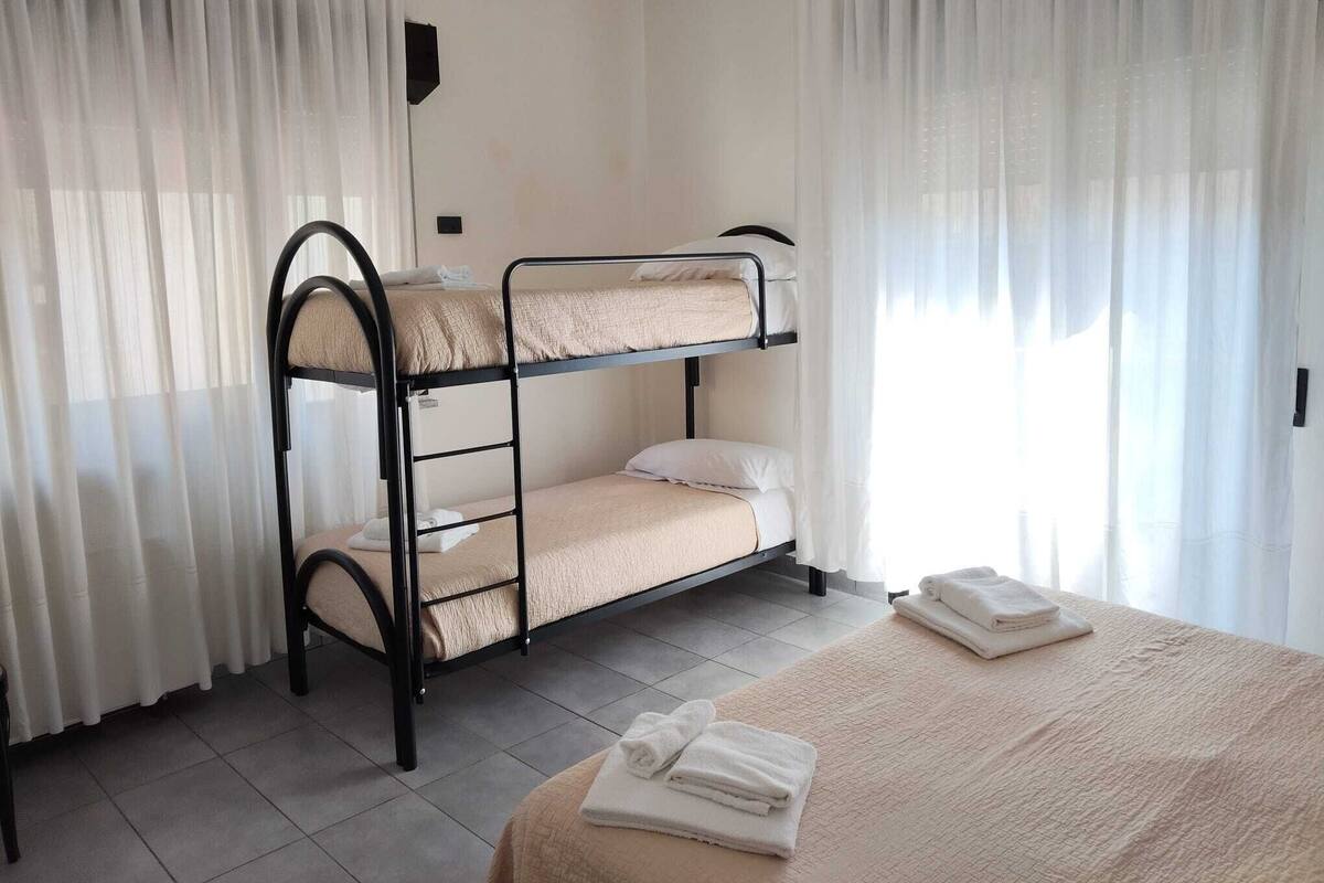 Een slaapkamer met een stapelbed, een bed en een kleine tafel.