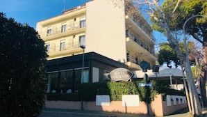 A hotel named 'Hotel Garisenda' with a modern facade, multiple balconies, and a clear view of the surrounding area.
