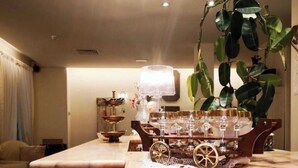 A wooden bar area with a cart holding glasses and a lamp.