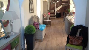 A hallway with a staircase leading to a loft area, a sofa with cushions, a lamp, a potted plant, and a chair with a handbag. - Large, comfortable Grand-Cosquet Locmaria house on 800m2 wooded grounds (Locmaria)