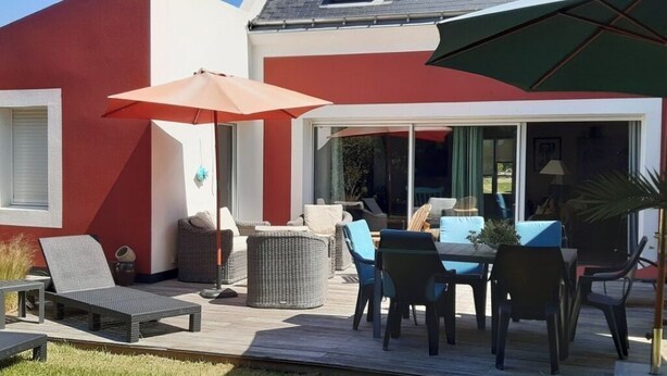 A patio with outdoor furniture, including a table and chairs, and a large umbrella. - Large, comfortable Grand-Cosquet Locmaria house on 800m2 wooded grounds (Locmaria)
