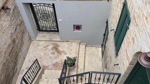 A courtyard with a stone staircase, a metal gate, and a small flower box. - La Dimora del Borgo (Montecassiano)