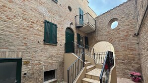 A narrow alleyway with a stone building, a staircase with metal railings, and a small balcony. - La Dimora del Borgo (Montecassiano)