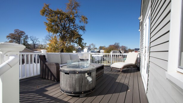 Une terrasse en bois avec un jacuzzi, des sièges d’extérieur et une vue sur le quartier.