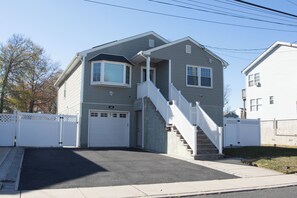 A two-story house with a front porch, a staircase, and a garage. - Charming newly renovated 3-bedroom house two blocks from sandy beach (Keansburg)