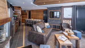 Un salon moderne avec une cheminée, un coin repas et un téléviseur fixé sur un mur en pierre.