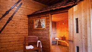 Une cabane en bois avec un banc, un espace sauna et une fenêtre avec un rideau.