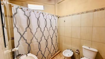 Un bagno con tenda doccia, due lavandini, un bidet e un water.