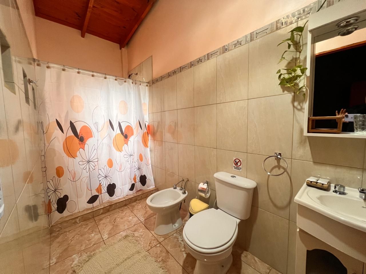 Un baño con cortina de ducha, un bidé, un inodoro y un lavabo.