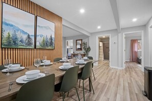 Enjoy meals in this stylish dining area with a long table, two large paintings, and natural light pouring in through the windows.