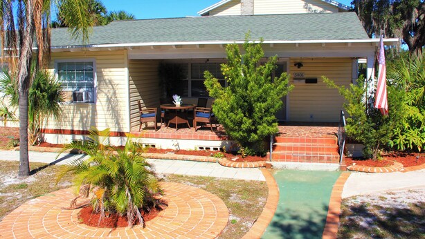 A two-story house with a covered patio, a small pool, and a flag.