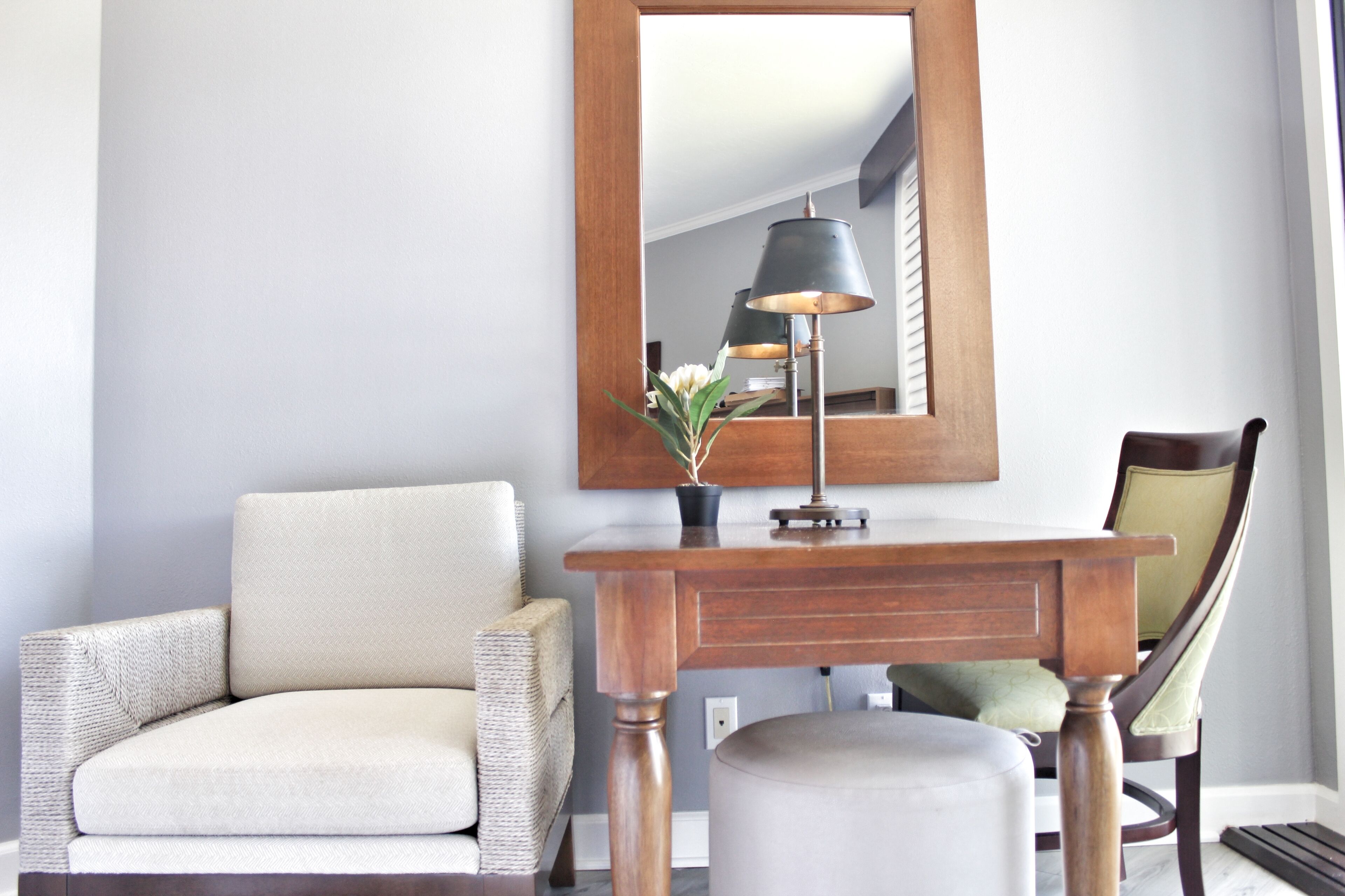 Une pièce comprenant une console en bois, une lampe, une chaise et un miroir.