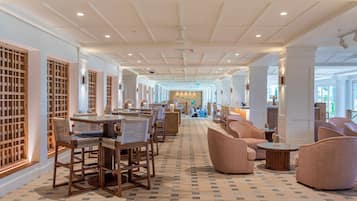 A hotel lobby with a long corridor, wooden furniture, and a patterned floor.