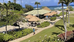 A resort with thatched-roof structures, a lawn, and palm trees. - Top Floor Ocean View at 4-Star Kauai Resort. Pools & Slides (Lihue)