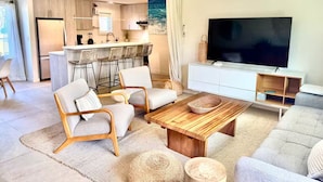 A modern living room with a sofa, chairs, a coffee table, and a TV.