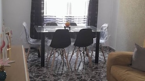 Un comedor con mesa y sillas de vidrio, una mesita con un globo terráqueo y un sofá al frente.