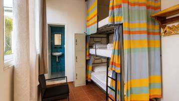 Un dormitorio con literas, un lavabo y una silla.