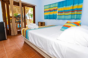 A hotel room with a bed, a small table, a chair, and a view of the outside.