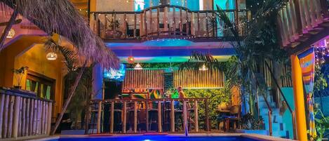 An indoor pool area with a bar and seating, surrounded by bamboo decor and plants.