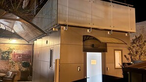 Un bâtiment moderne et compact, doté d’un toit plat et d’une grande entrée illuminée.