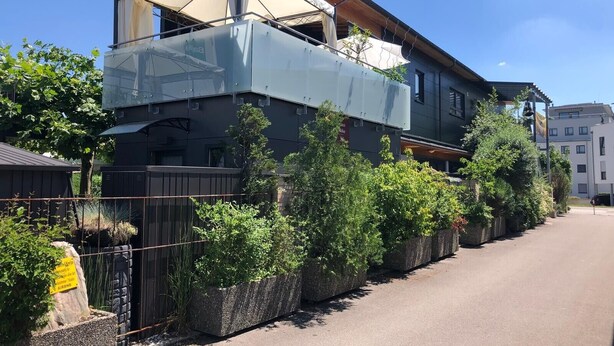 Un bâtiment moderne  à deux étages, doté d’un balcon couvert et d’un espace jardin agrémenté de diverses plantes.