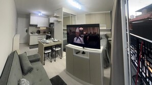A modern kitchen with white cabinets, a dining area with a table and chairs, and a TV mounted on a cabinet. - Studio 5 minutes from the Metro, Expo Center Norte, Anhembi (Tucuruvi São Paulo)