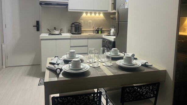A modern kitchen with white cabinets, a dining table set for four, and a refrigerator. - Studio 5 minutes from the Metro, Expo Center Norte, Anhembi (Tucuruvi São Paulo)