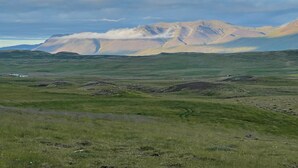 Un paisaje extenso y abierto con colinas ondulantes y una cordillera en el fondo.
