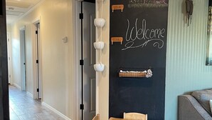 A dining area with a wooden table and chairs, a chalkboard wall with seasonal decorations, and a clock.
