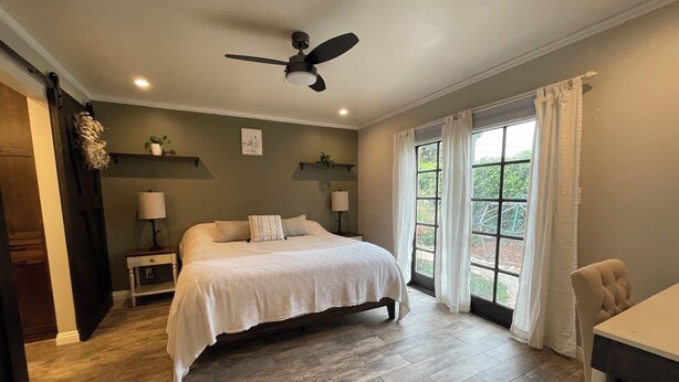A bedroom with a bed, bedside tables, a ceiling fan, and a window with curtains.