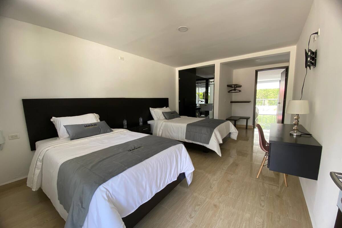 A hotel room with two beds, a desk, and a chair.