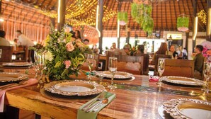 A restaurant with wooden tables, floral centerpieces, and hanging plants. - MALOKAS RESORT (Socorro)