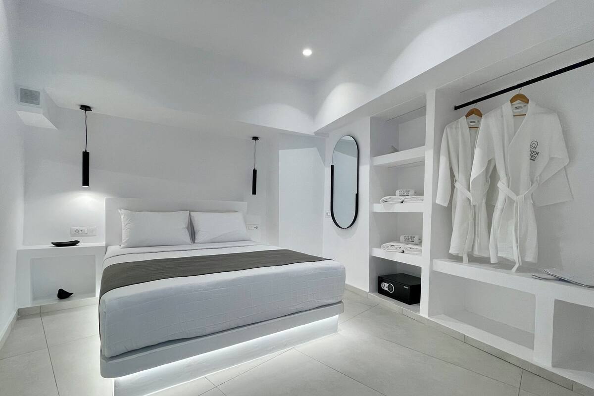 A modern bedroom with a bed, bedside tables, a mirror, and a robe rack.