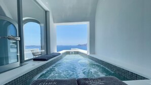 En modern inomhuspool med fri utsikt över havet och ett berg i fjärran.