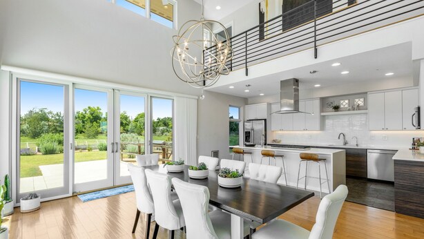 A modern kitchen with white cabinets, a stainless steel refrigerator, and a large island with stools. - Perfectly Between Boulder - Estes Park! Modern 5-Bedroom House (Longmont)